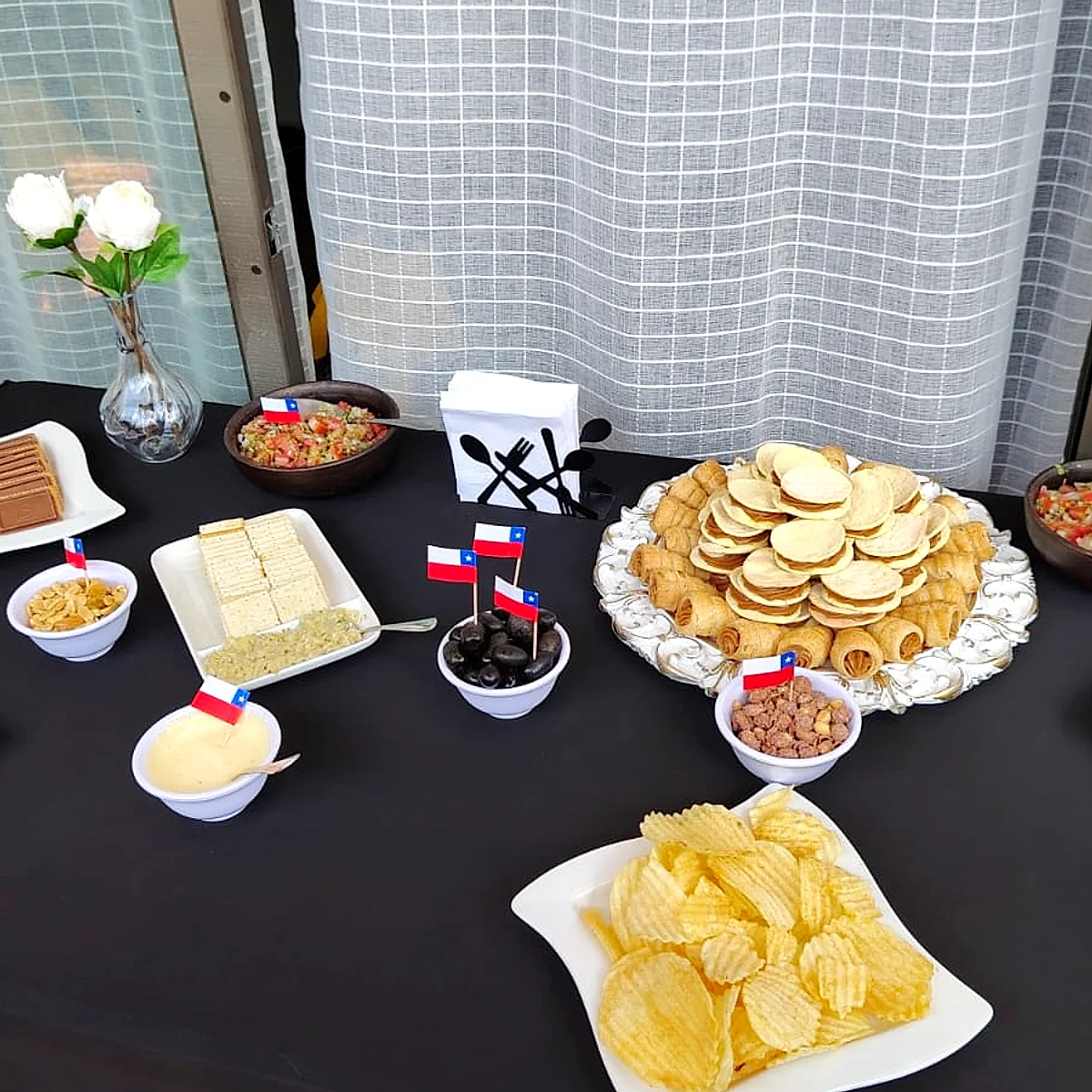 Mesa de cóctel con bocados dulces y salados sobre mantel negro