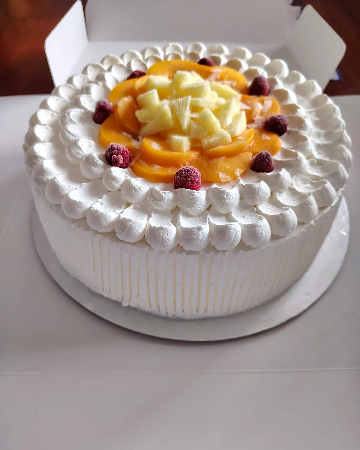 Torta de crema decorada con durazno y frambuesas